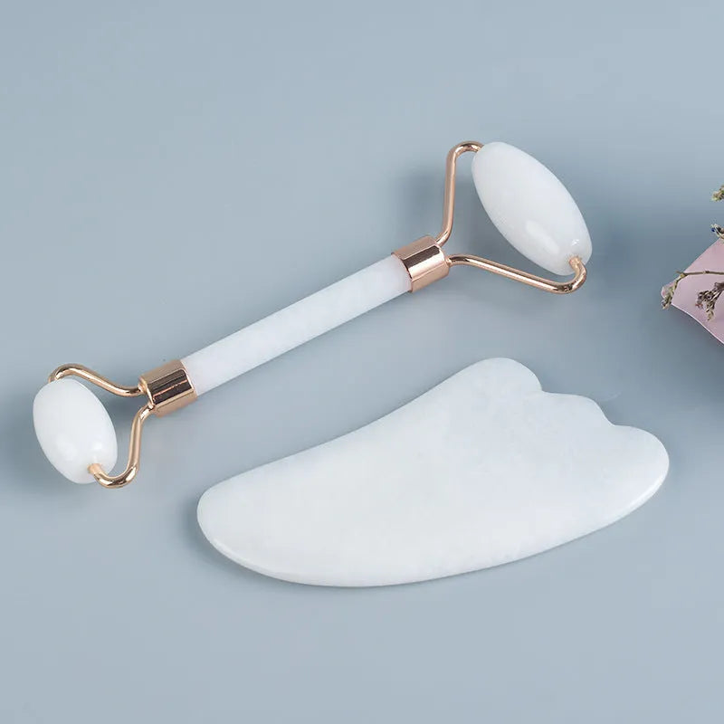 White jade double-headed facial roller and gua sha scraping tools on wooden storage board
