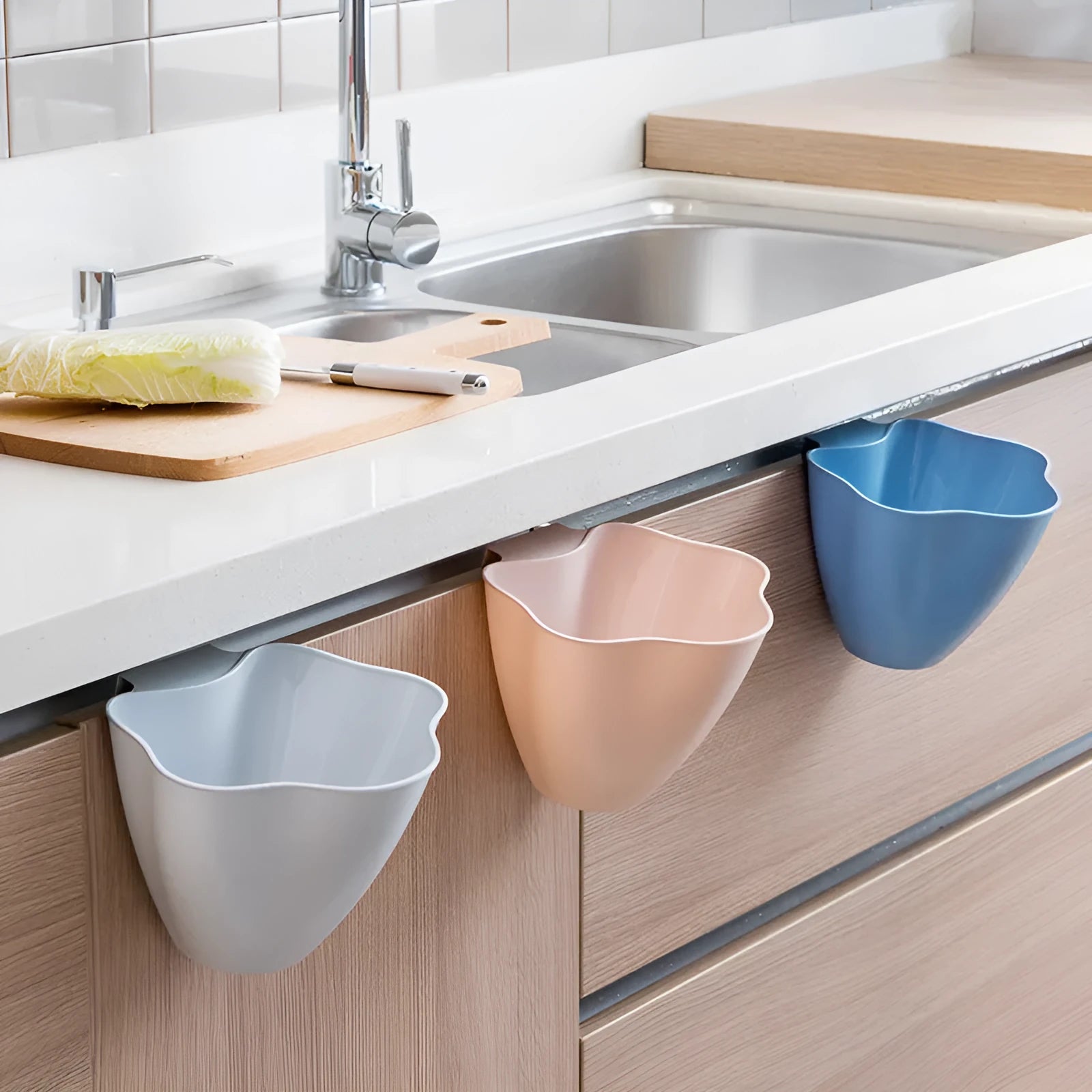 Compact pedal-operated kitchen bin in Nordic blue colour placed inside a wooden cabinet.