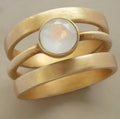 Gold-plated geometric ring with a white chalcedony stone micro-inlaid in a hollow setting.