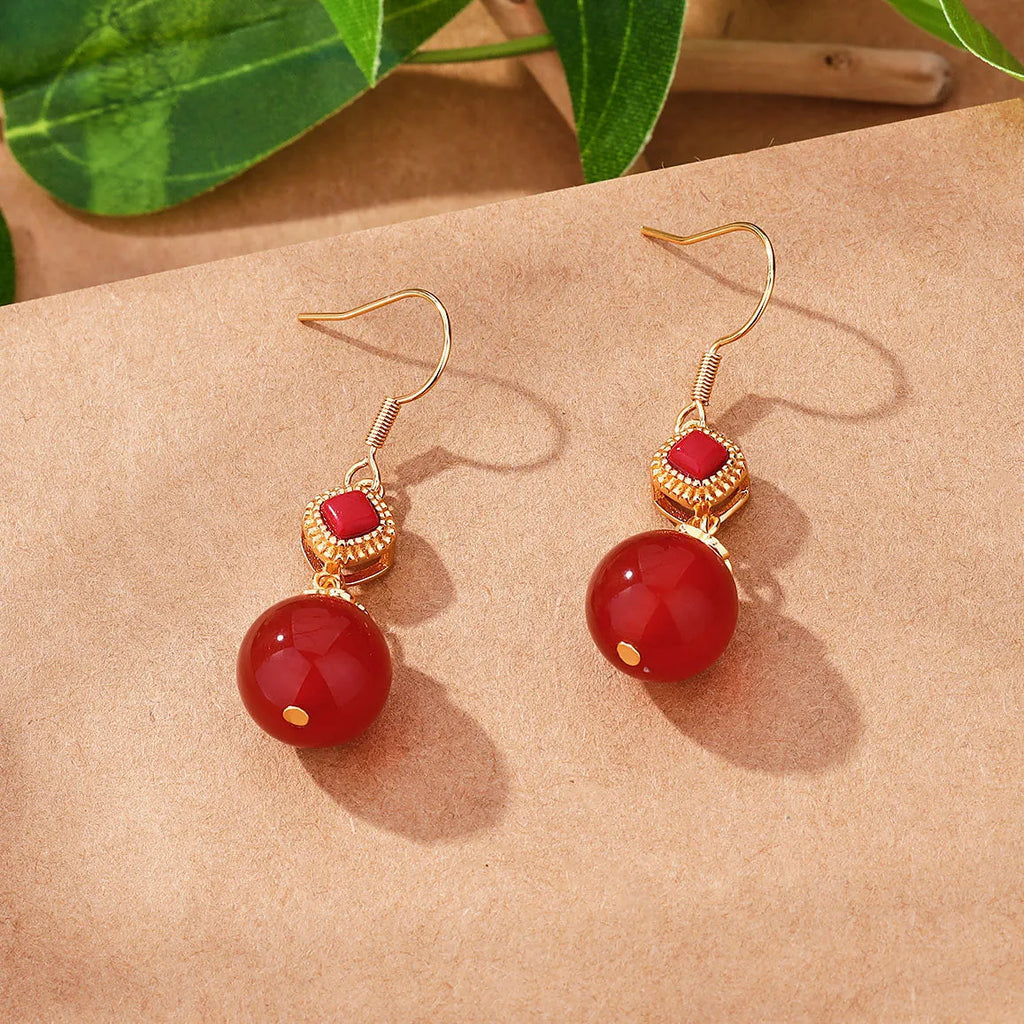 Geometric drop earrings with red agate round beads and sterling silver inlaid jasper stones on a copper base.