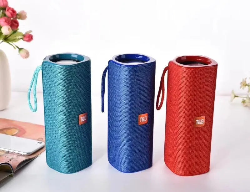 Cloth-covered wireless Bluetooth speaker in multiple colours showing front with speaker grilles