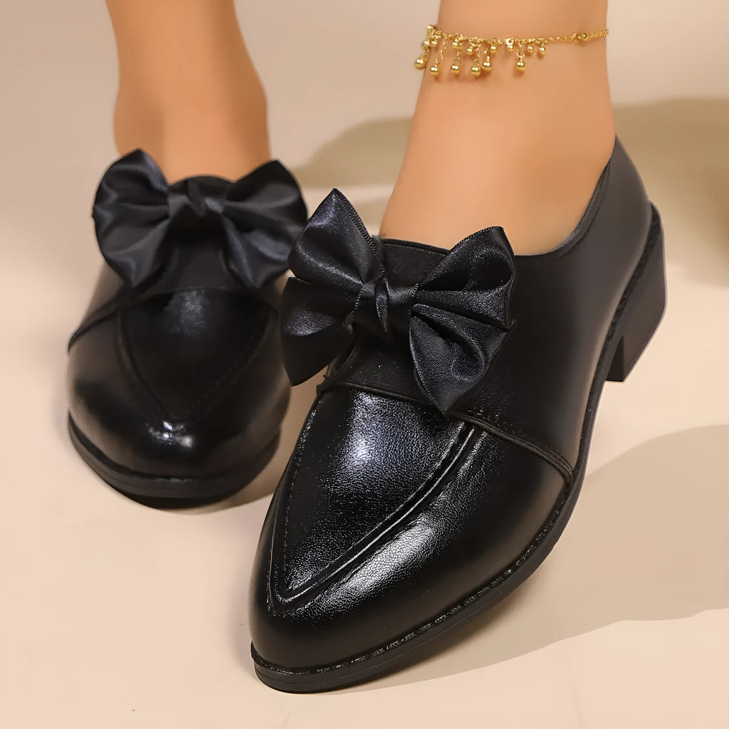 Women's simple slip-on shoe in a British-style leather look with a choice of buckle or bow decoration on the upper.
