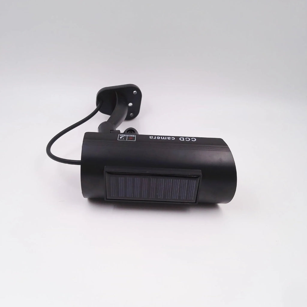 Black plastic gun-shaped dummy security camera with solar panel and red LED light indicator