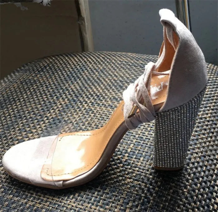 Black and gold plastic high heels with a pointed toe on a white background.