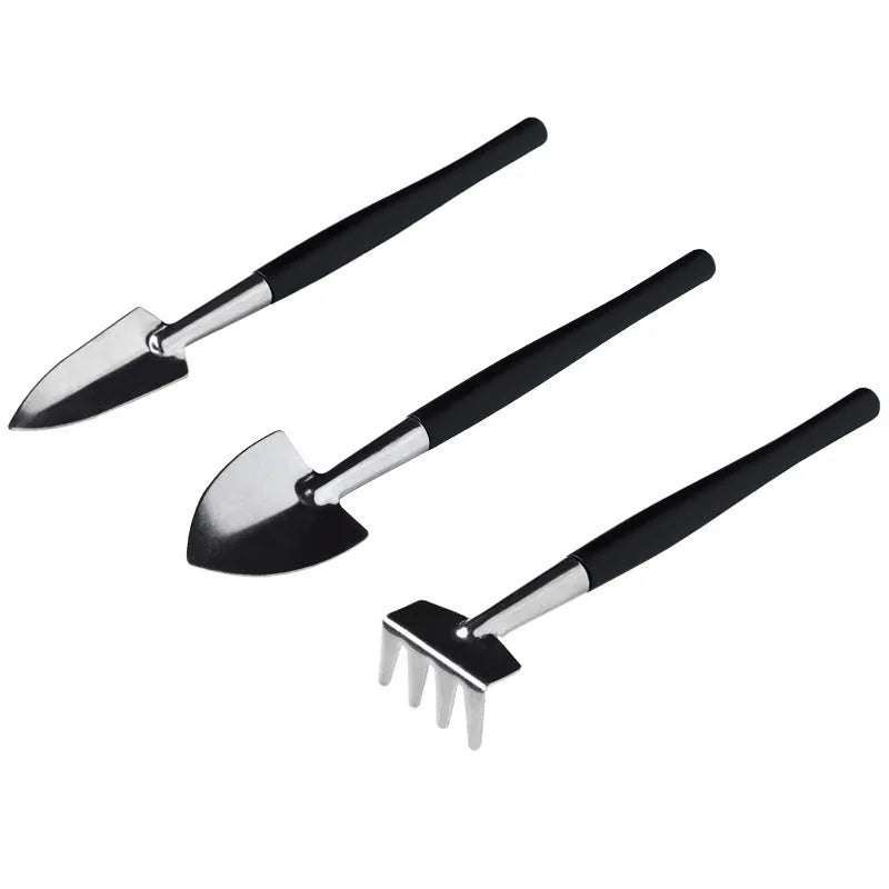 Black succulent garden tools set with shovel, tweezers, scissors, watering bottle and a square grey cushion.