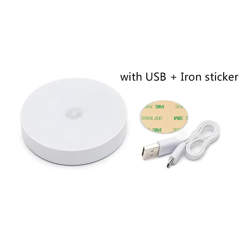Small round white LED night light with motion sensor and USB charging cable on a table.