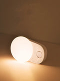 White rechargeable LED night light with motion sensor for bedside use.