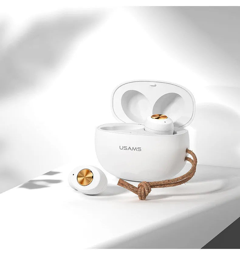 Wireless black TWS earbuds next to their small white charging case on a table.