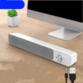 G18 black and white compact desktop computer speaker with USB cable on a wooden desk.