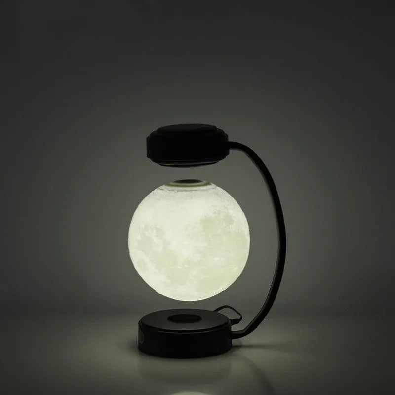 Black and gold magnetic levitation moon lamp with three-colour light changing on bedside table