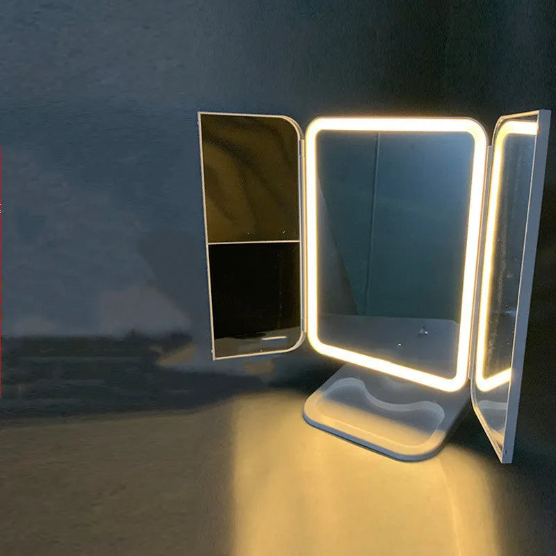 Trifold LED makeup mirror with 68 lights, 10X detachable magnifier, silver surface, rotating 180 degrees on a tabletop