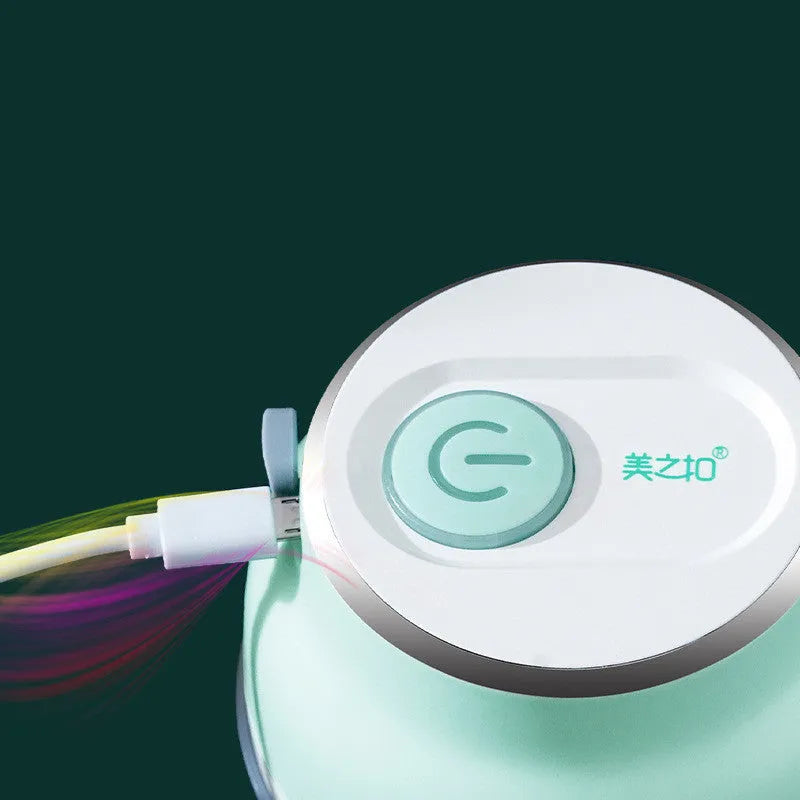 Mini electric food chopper with transparent cup and stainless steel blade on a kitchen counter.