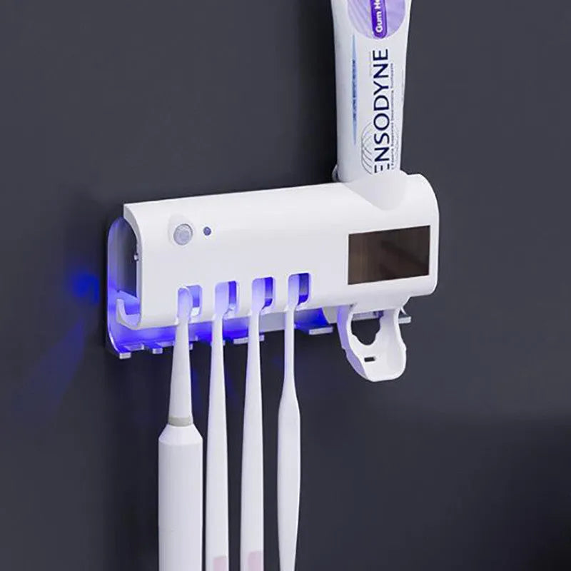 Black and white wall-mounted UV toothbrush steriliser with automatic toothpaste squeezer, showing solar panel and sensor.