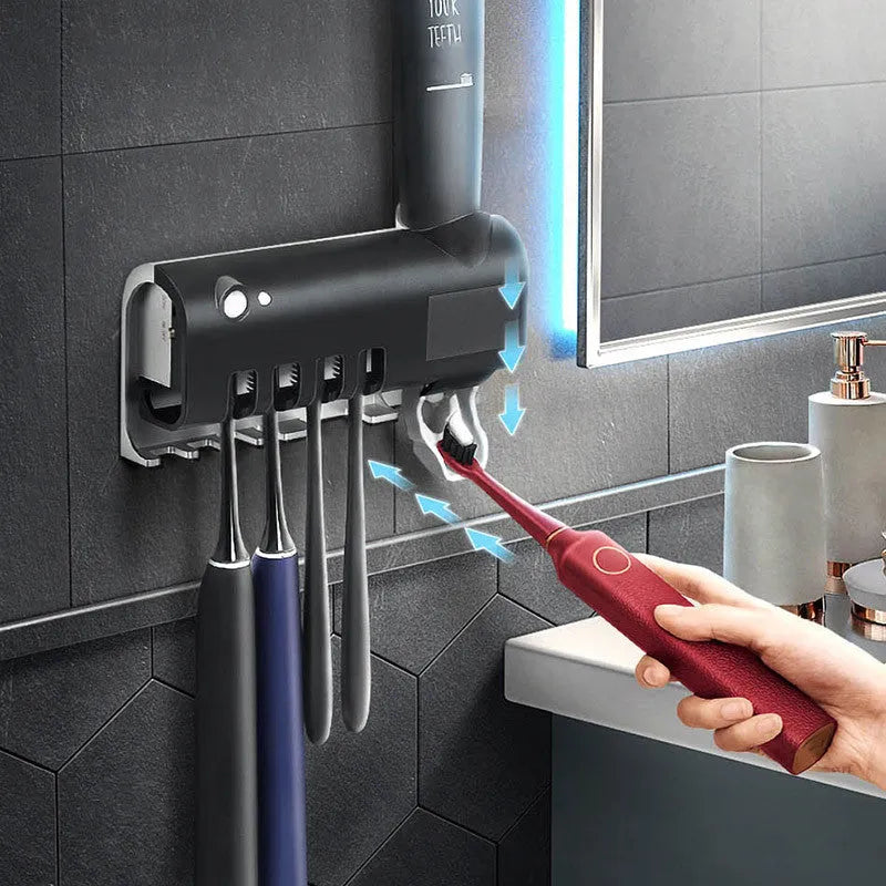 Black and white wall-mounted UV toothbrush steriliser with automatic toothpaste squeezer, showing solar panel and sensor.