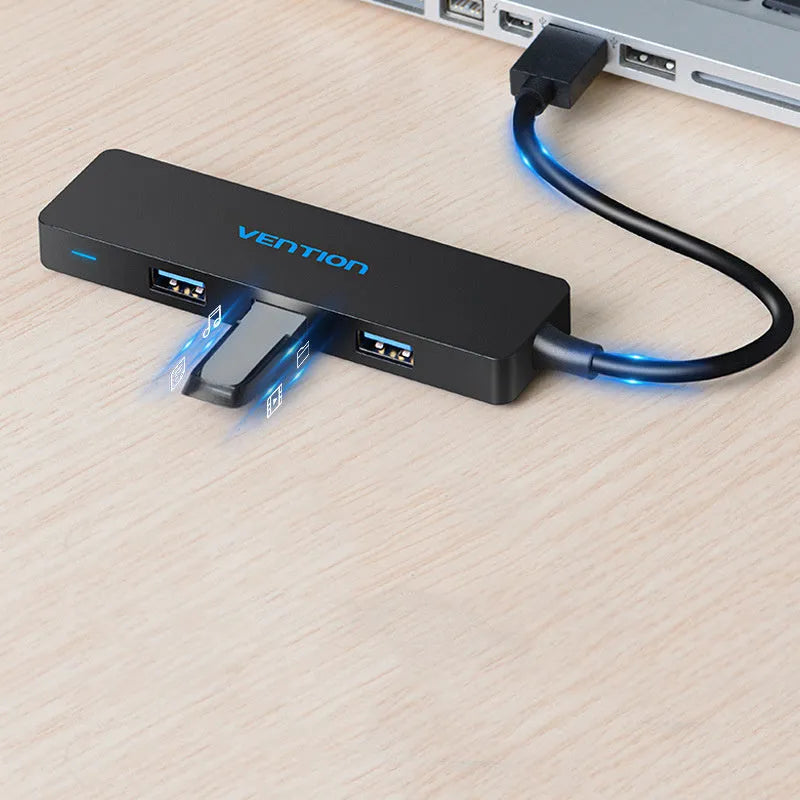 Black four-port USB 3.0 hub splitter with a short connected cable on a desktop.