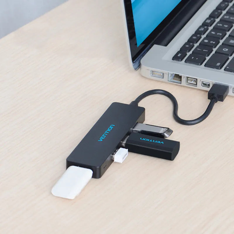 Black four-port USB 3.0 hub splitter with a short connected cable on a desktop.
