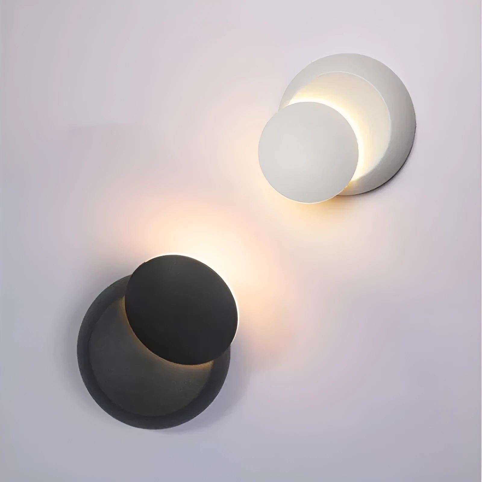 Rotating lunar eclipse LED wall lamp with aluminium shade in black finish on a living room wall