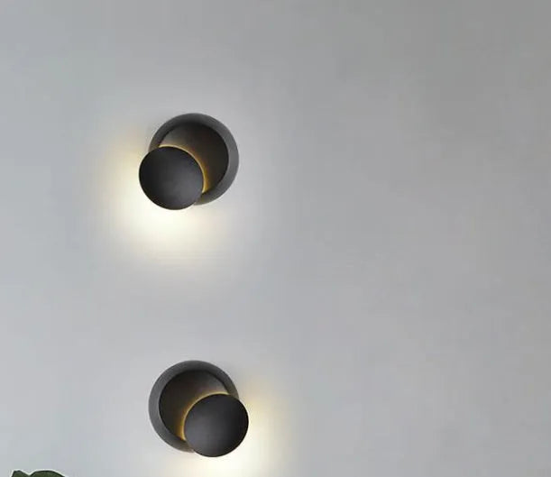 Rotating lunar eclipse LED wall lamp with aluminium shade in black finish on a living room wall