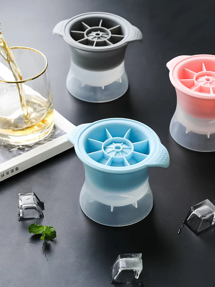 Flexible silicone ice tray producing large ice spheres, hockey puck shapes, and pentagon ice on a kitchen counter.