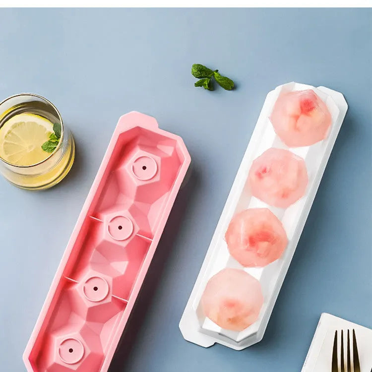 Flexible silicone ice tray producing large ice spheres, hockey puck shapes, and pentagon ice on a kitchen counter.