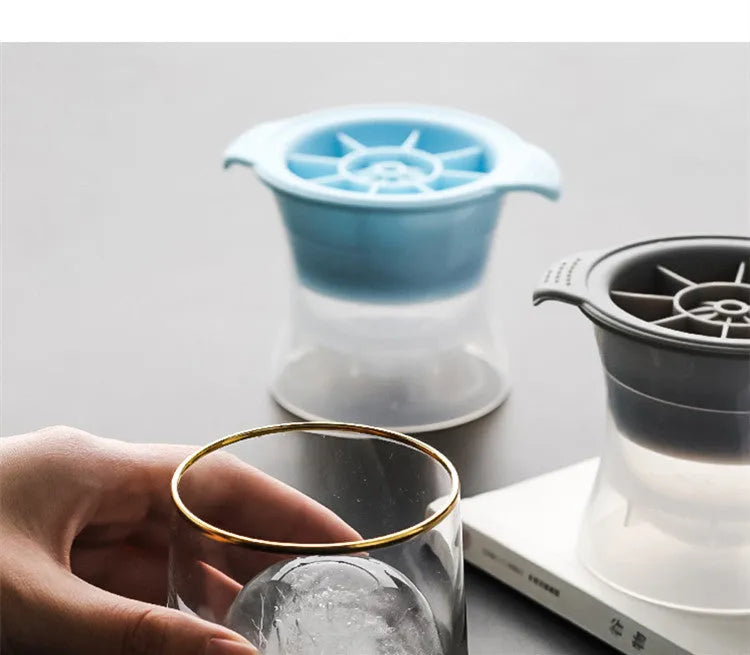 Flexible silicone ice tray producing large ice spheres, hockey puck shapes, and pentagon ice on a kitchen counter.