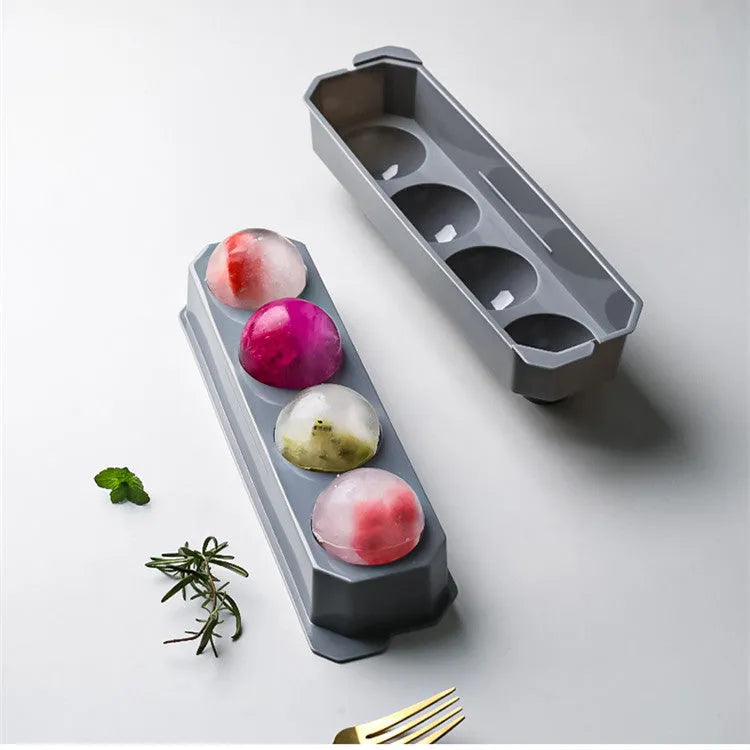 Flexible silicone ice tray producing large ice spheres, hockey puck shapes, and pentagon ice on a kitchen counter.