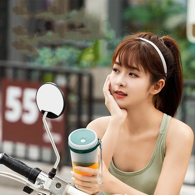 Portable pink or green electric juicer cup with USB charging port and removable lid.