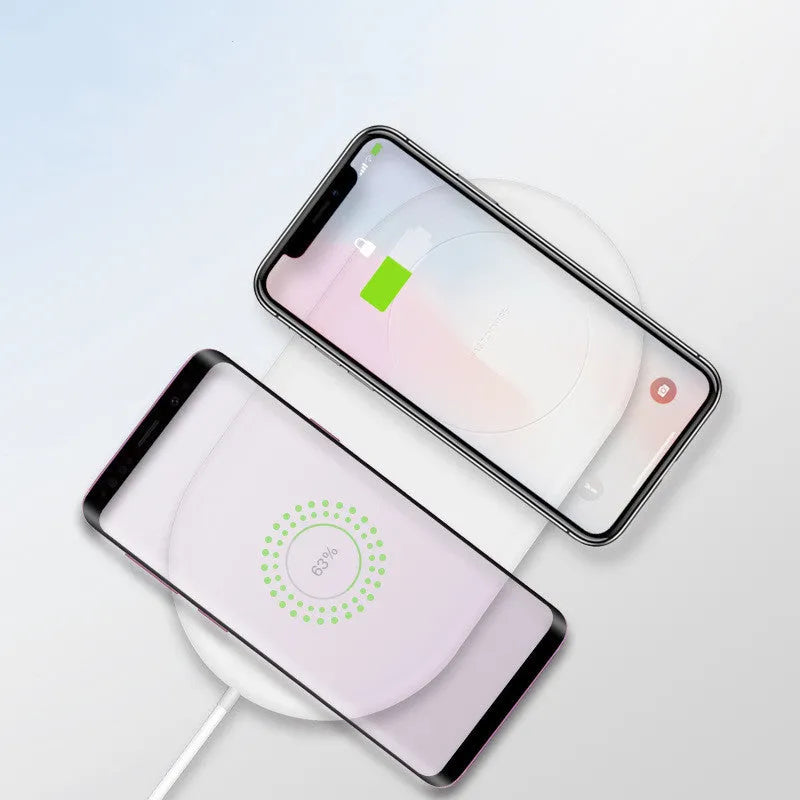 White dual wireless phone charger charging two mobile phones simultaneously on tabletop