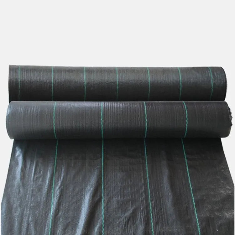 Black polyethylene weed-proof ground cover cloth laid flat on soil, showing woven texture.