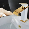 Black and white brass basin faucet with gold accents and waterfall water flow design