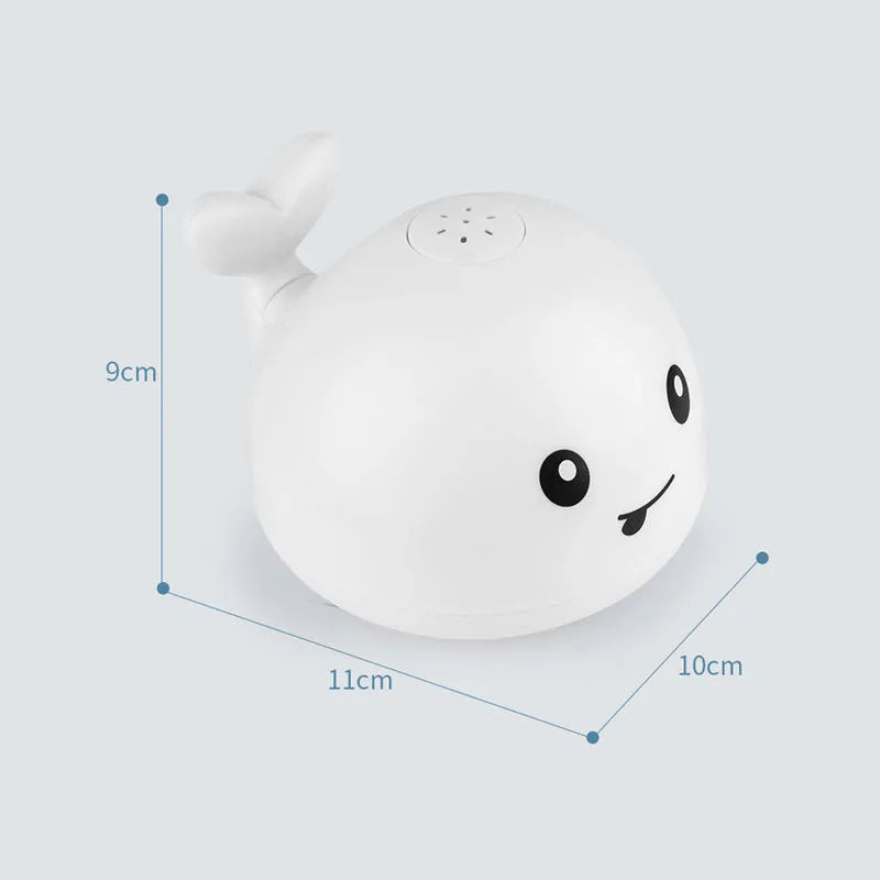 White and blue electric whale bath toy spraying water with flashing lights on a bathroom surface.