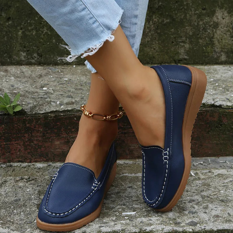 Women's flat PU leather loafers in multiple colours showing round toe and car suture detail.
