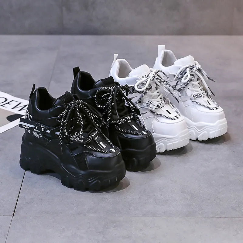 White and black women's low-top platform sports shoes with a cross strap and mesh upper.