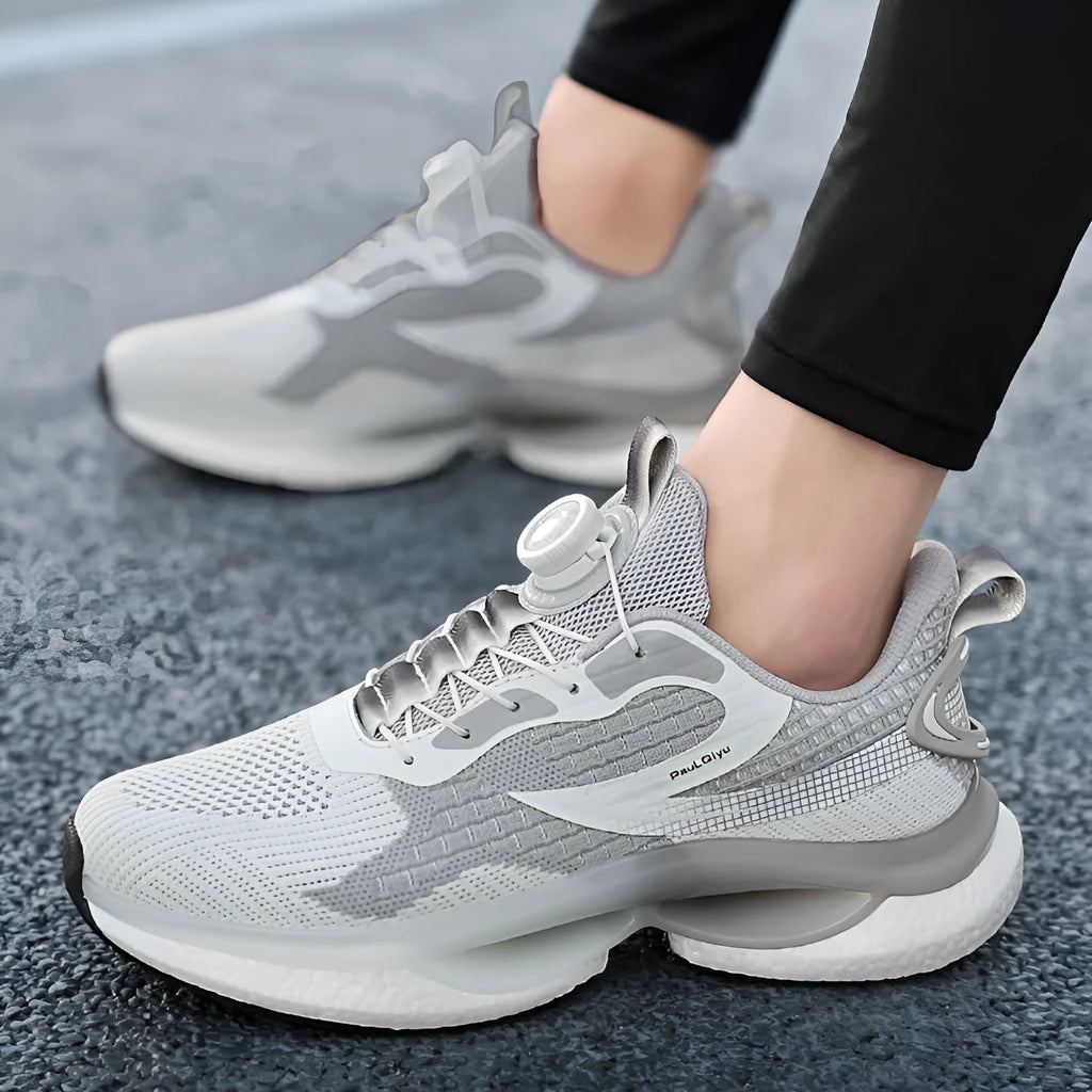 Men's beige Korean style running shoes with rotating button closure on a grey background.