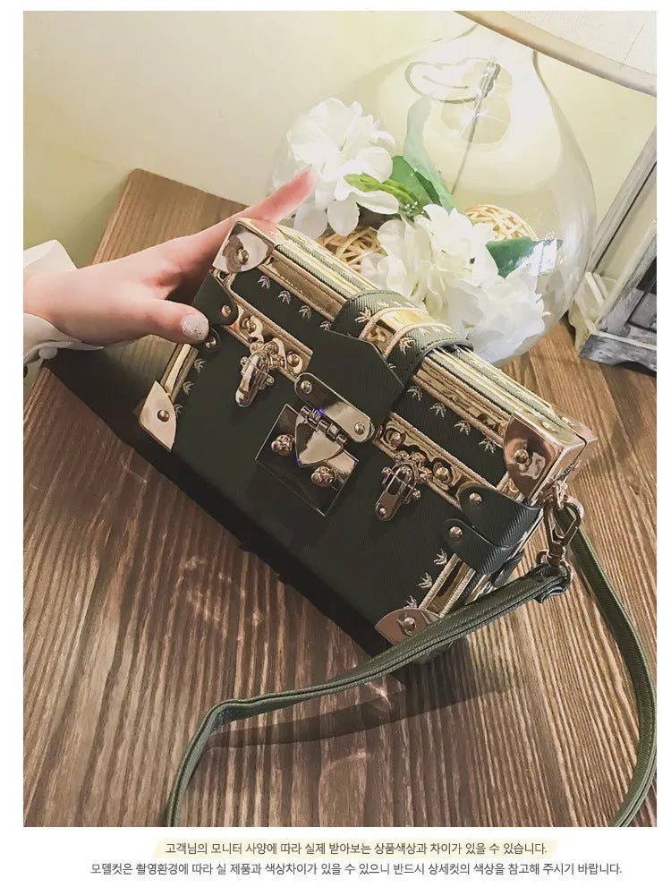 Women's hard black flap handbag with single strap, rivet details, and hasp closure.