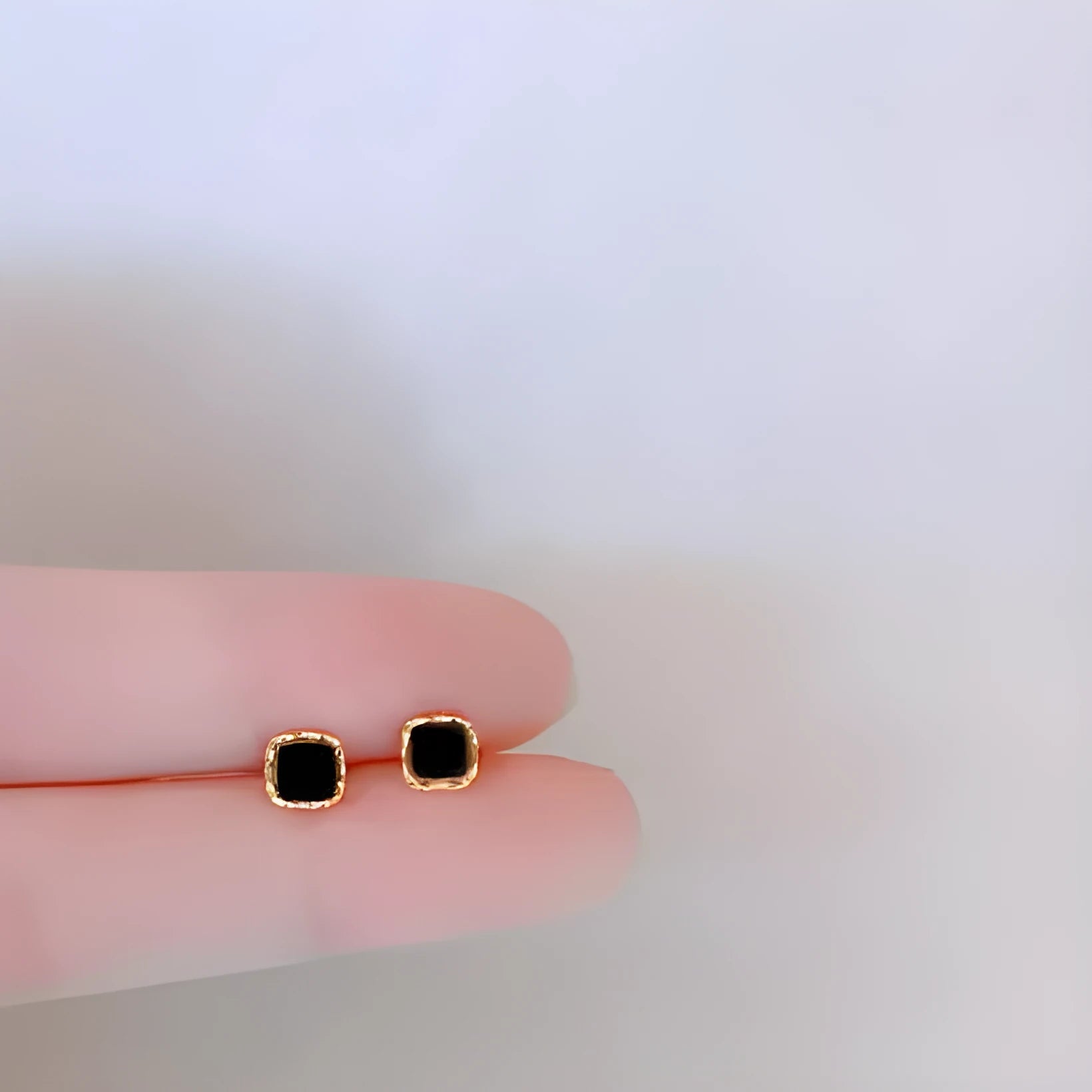 Black round mini ear studs in sterling silver plating with inlaid zircon on white background