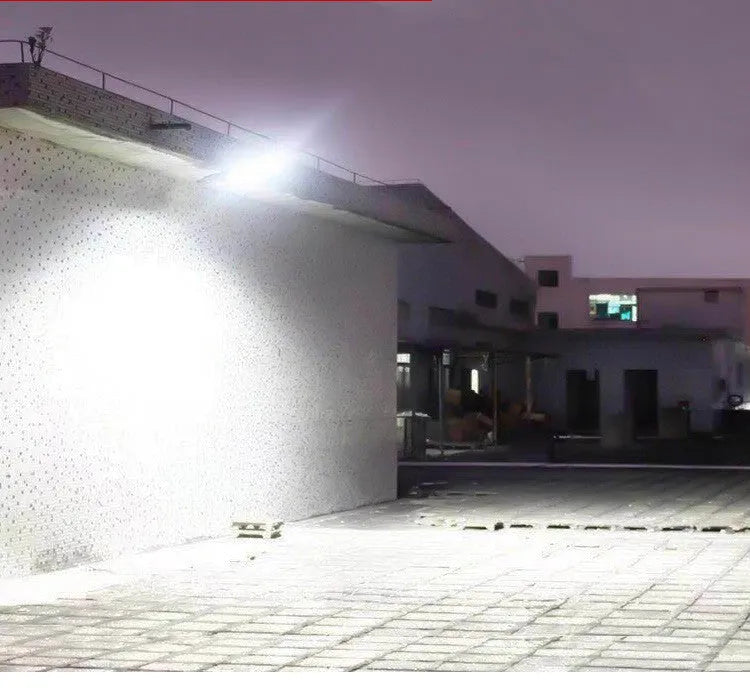 Black outdoor solar-powered security light with motion sensor on a wall.
