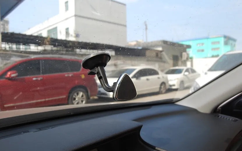 Black magnetic car phone holder mounted on a dashboard, showing a smartphone attached at an angle.