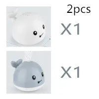 White and blue electric whale bath toy spraying water with flashing lights on a bathroom surface.