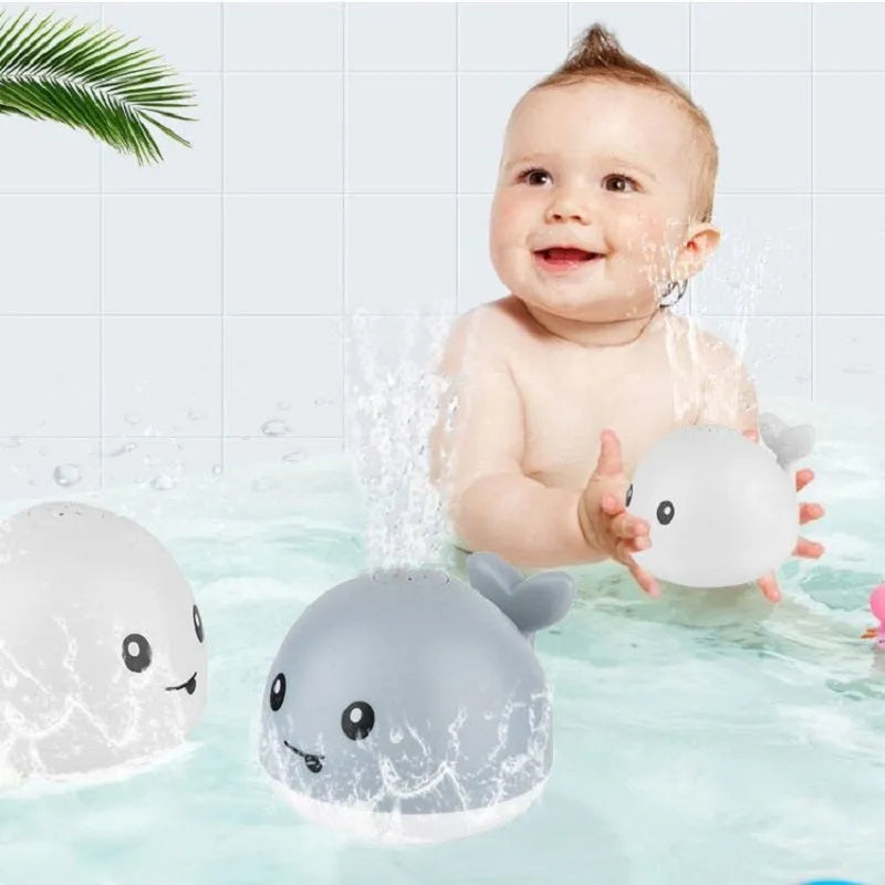 White and blue electric whale bath toy spraying water with flashing lights on a bathroom surface.