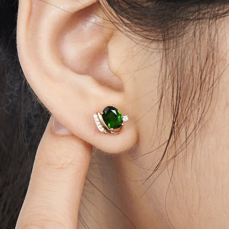 Pair of green ghost crystal stud earrings in silver with diamond-cut geometric shape on white background