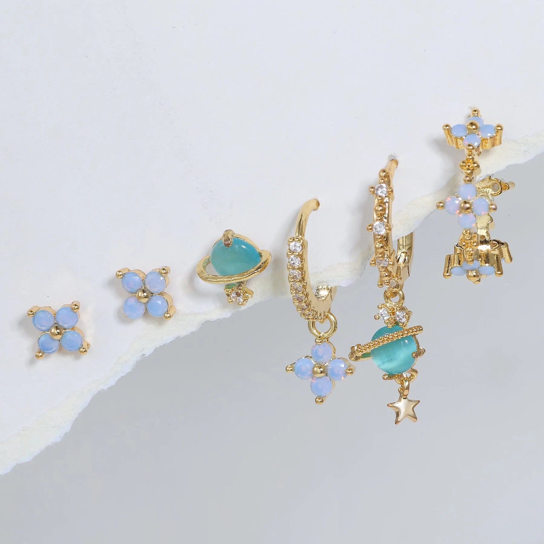 Gold and silver Japanese Korean style stud earrings with blue flower nail shape and zircon mosaic detail.