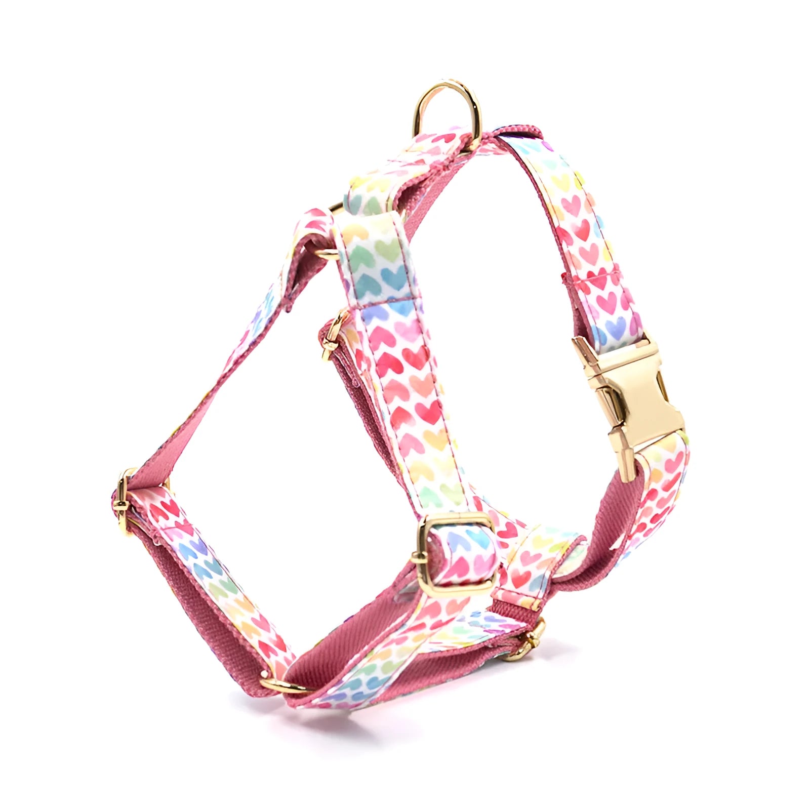 Pink colourful dog harness with gold buckle and heart-shaped stone decoration on a white background.