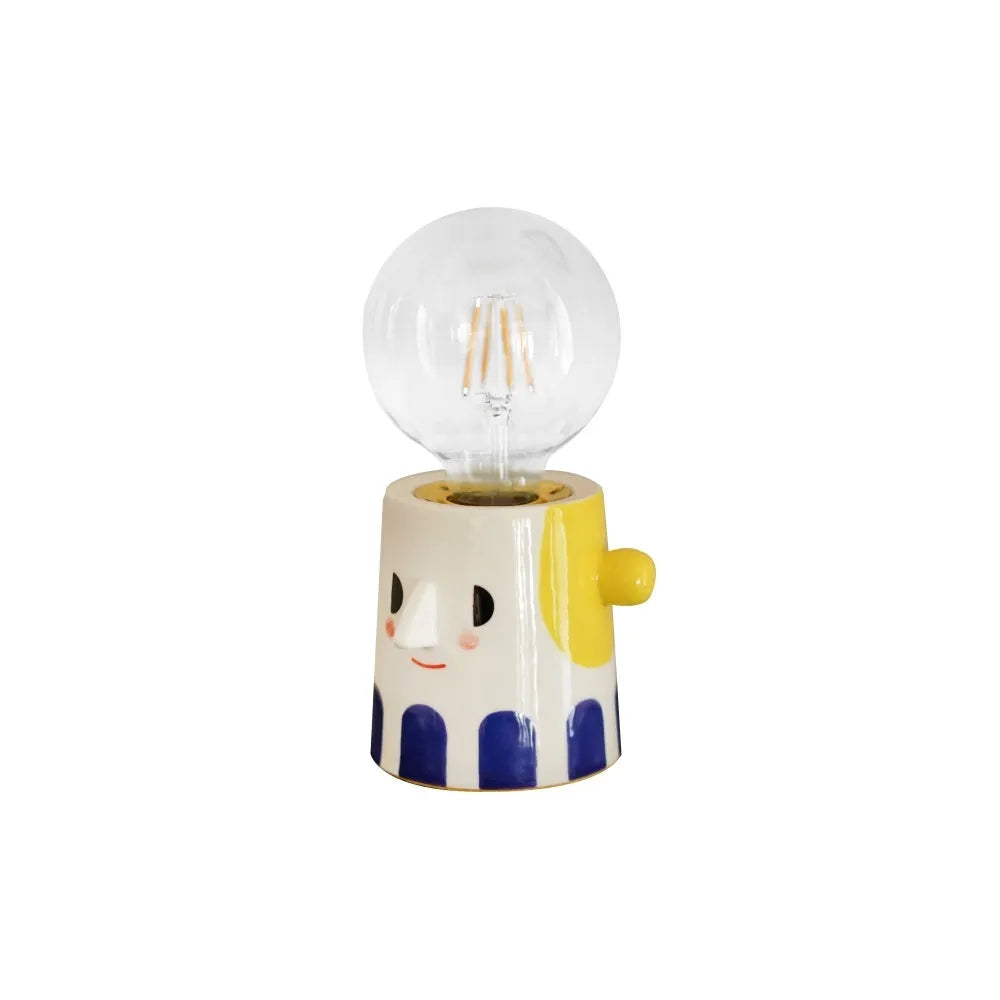 Handmade ceramic bedside lamp with a ball headlight design on a nightstand.