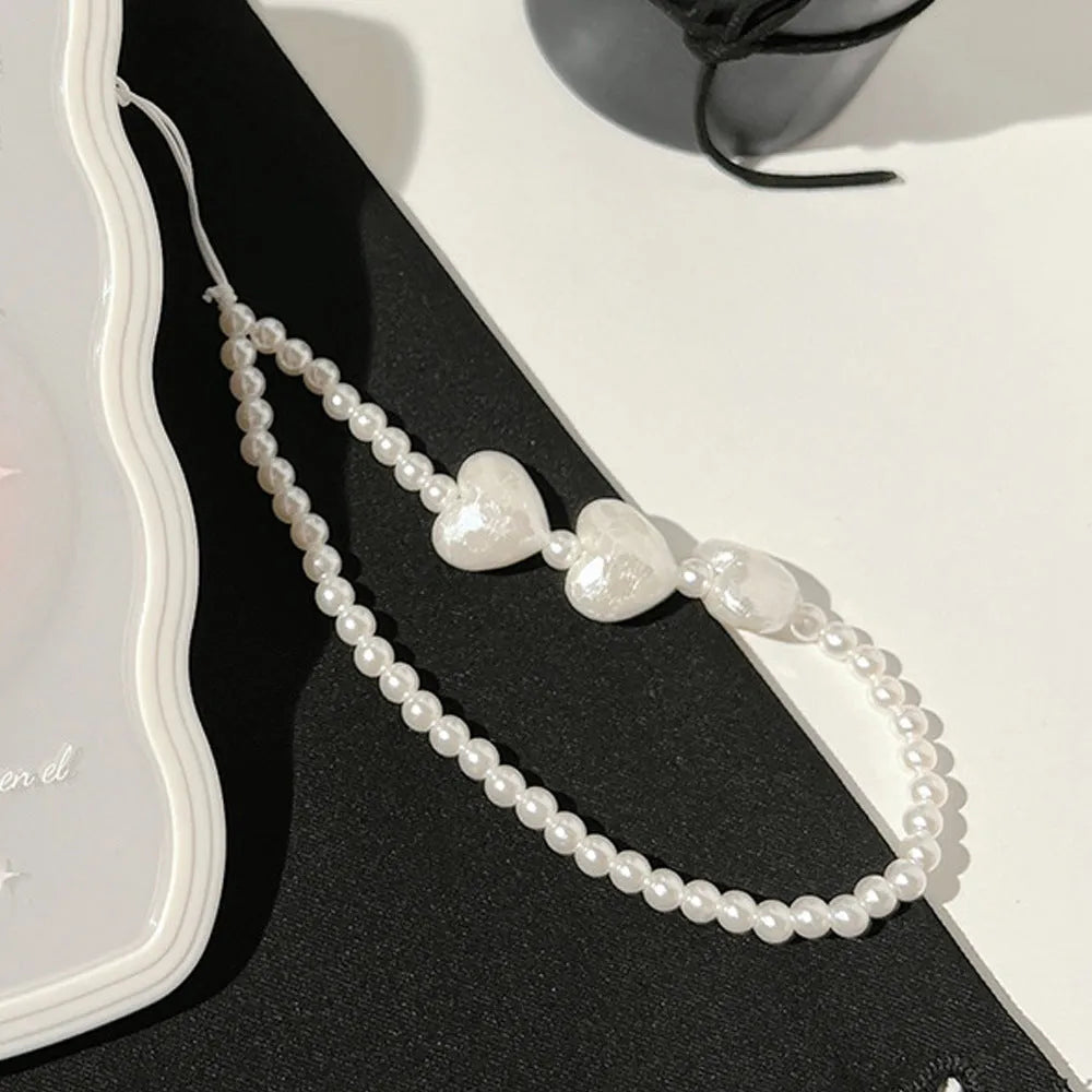 Clear iPhone case with a raised 3D bow design and a white love lanyard on a table.
