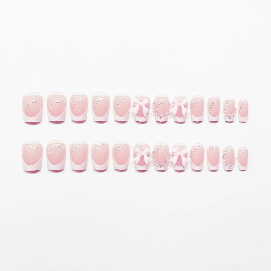 Short artificial French manicure nails with white bow, tulip, and starry sky designs on a square tip.