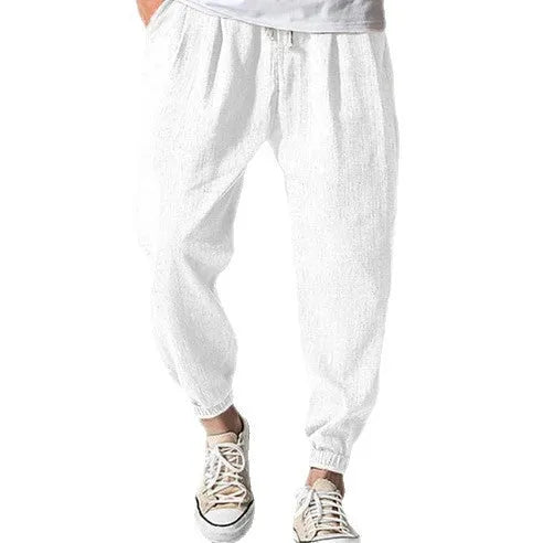 Man wearing loose light-coloured cotton trousers with elasticated ankle cuffs, showing front and side views.
