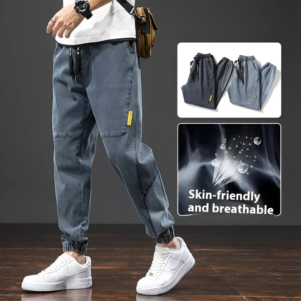 Man wearing loose straight leg cargo jeans in blue, showing mid waist and zipper fly detail.
