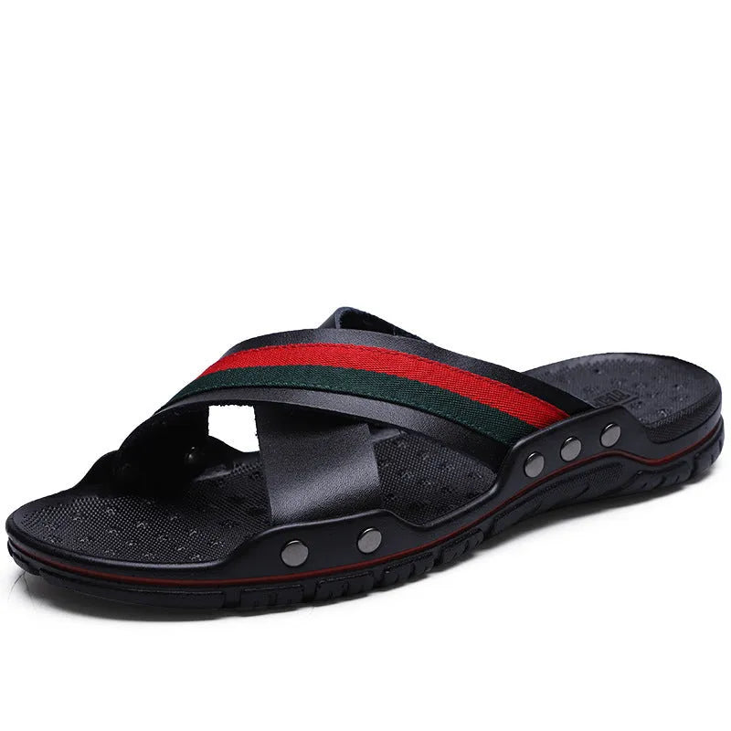 Men's black cowhide flip-flops with a textured non-slip PU sole on a sandy beach.