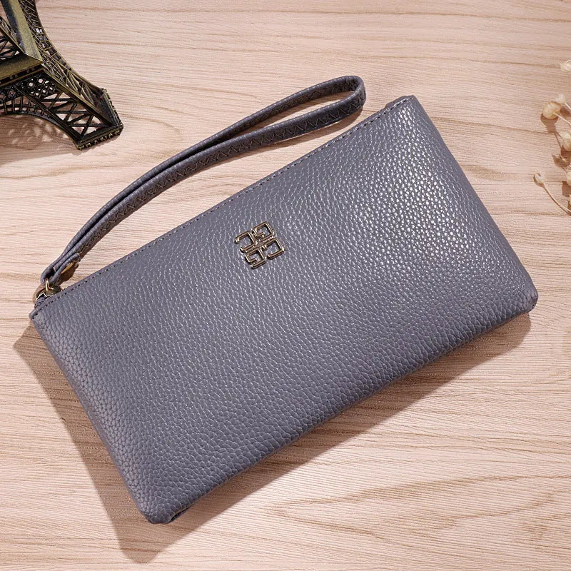 Woman holding a wine red zip-around PU leather phone wallet handbag with a 55-inch long strap.